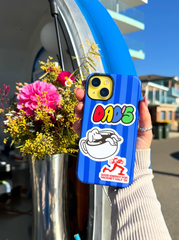 A blue phone case with a Dad's sticker held up beside a vase of flowers at the trailer